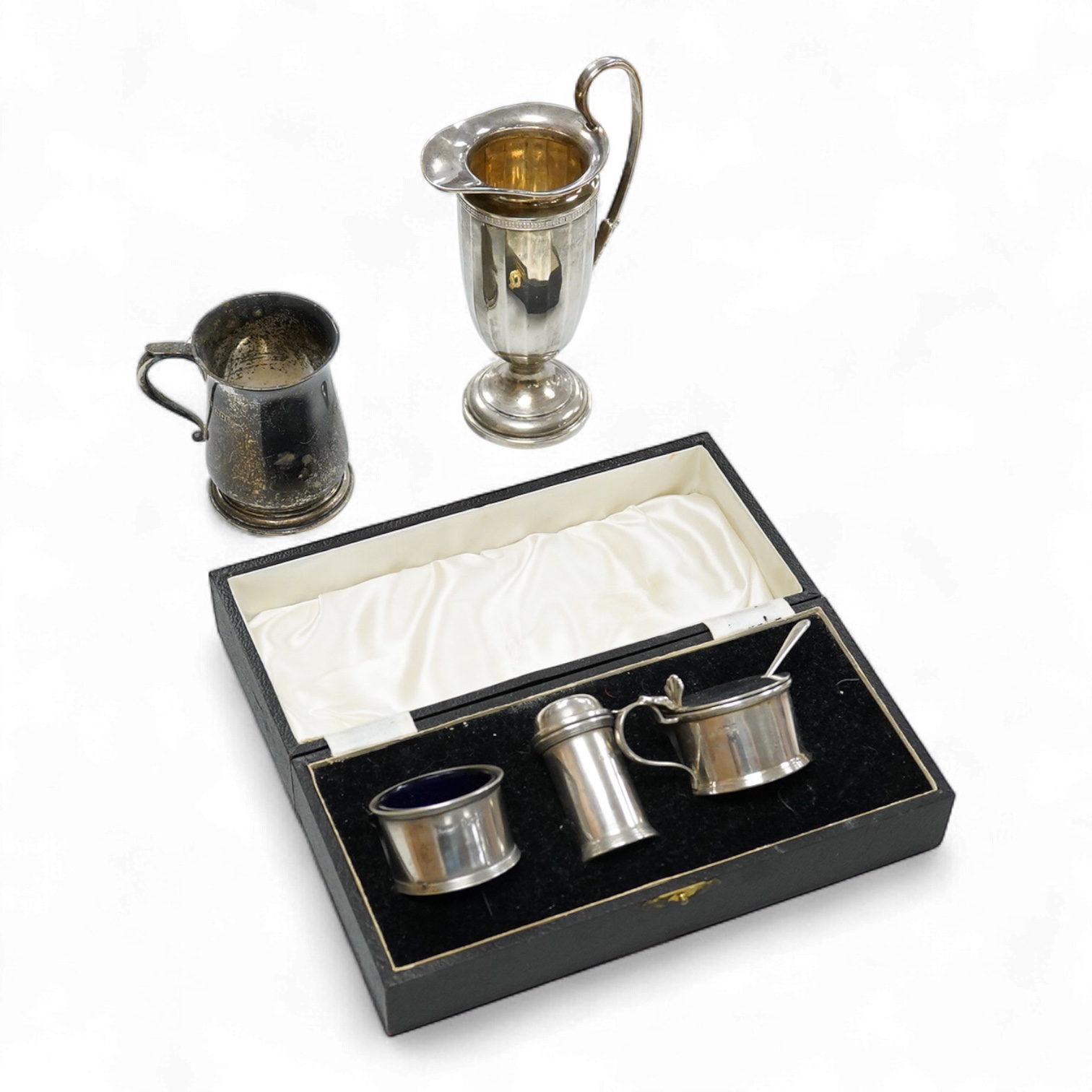 A George V silver tall cream jug, Birmingham, 1930, 17.2cm, a 1950's silver small mug, London, 1955 and a cased 1930's silver three piece condiment set.